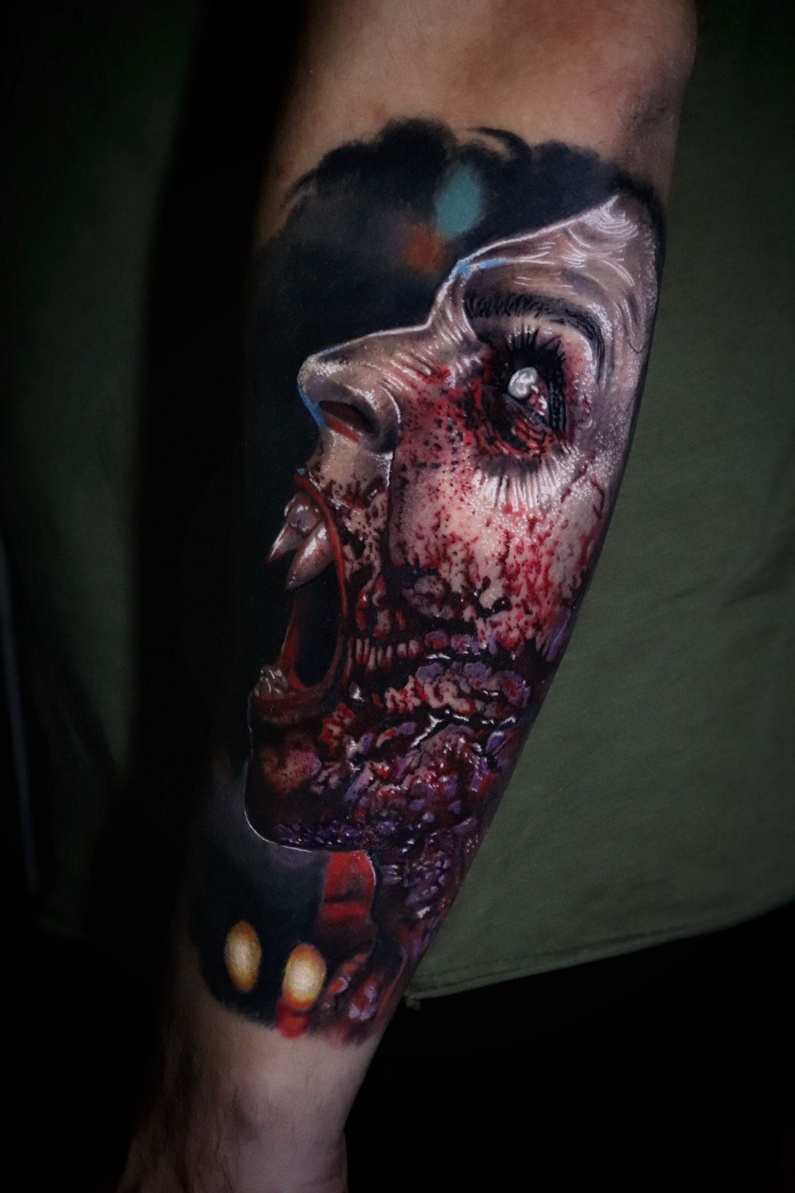 11dlhzmxg7ben5kkpcawmgw-1 Tatuagem realista em um braço, mostrando um rosto com expressão dramática e detalhes sombrios e coloridos.