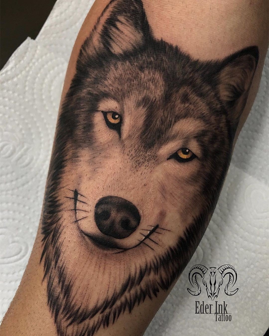 18zttnaqlo3pqjifr-dafbw Tatuagem realista de lobo em um braço, destacando olhos amarelos e detalhes do pelo.