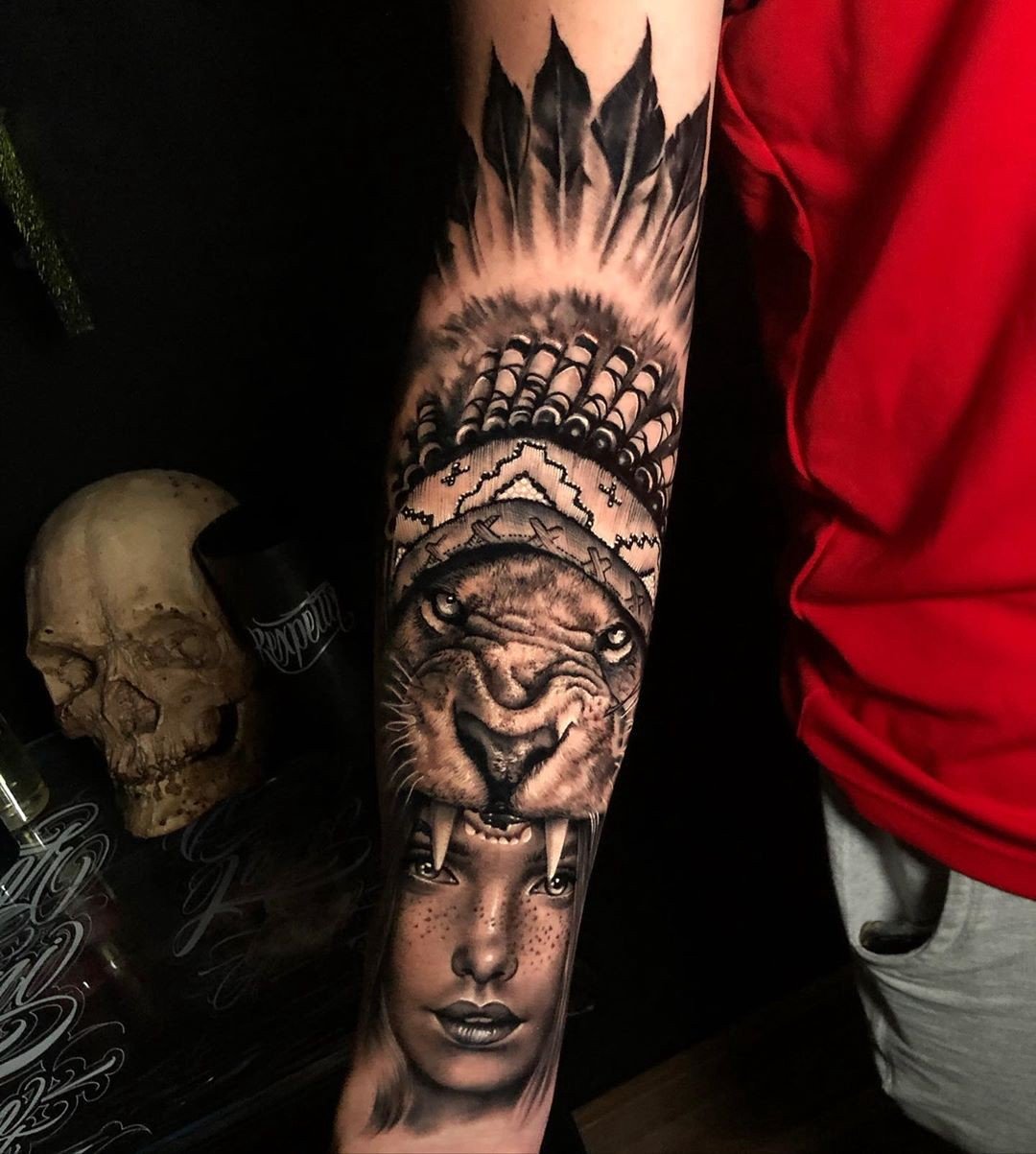 1b3kp2jahsbaik_yw2kid9q Braço tatuado com desenho de tigre e rosto, ao lado de um crânio e camiseta vermelha visível.