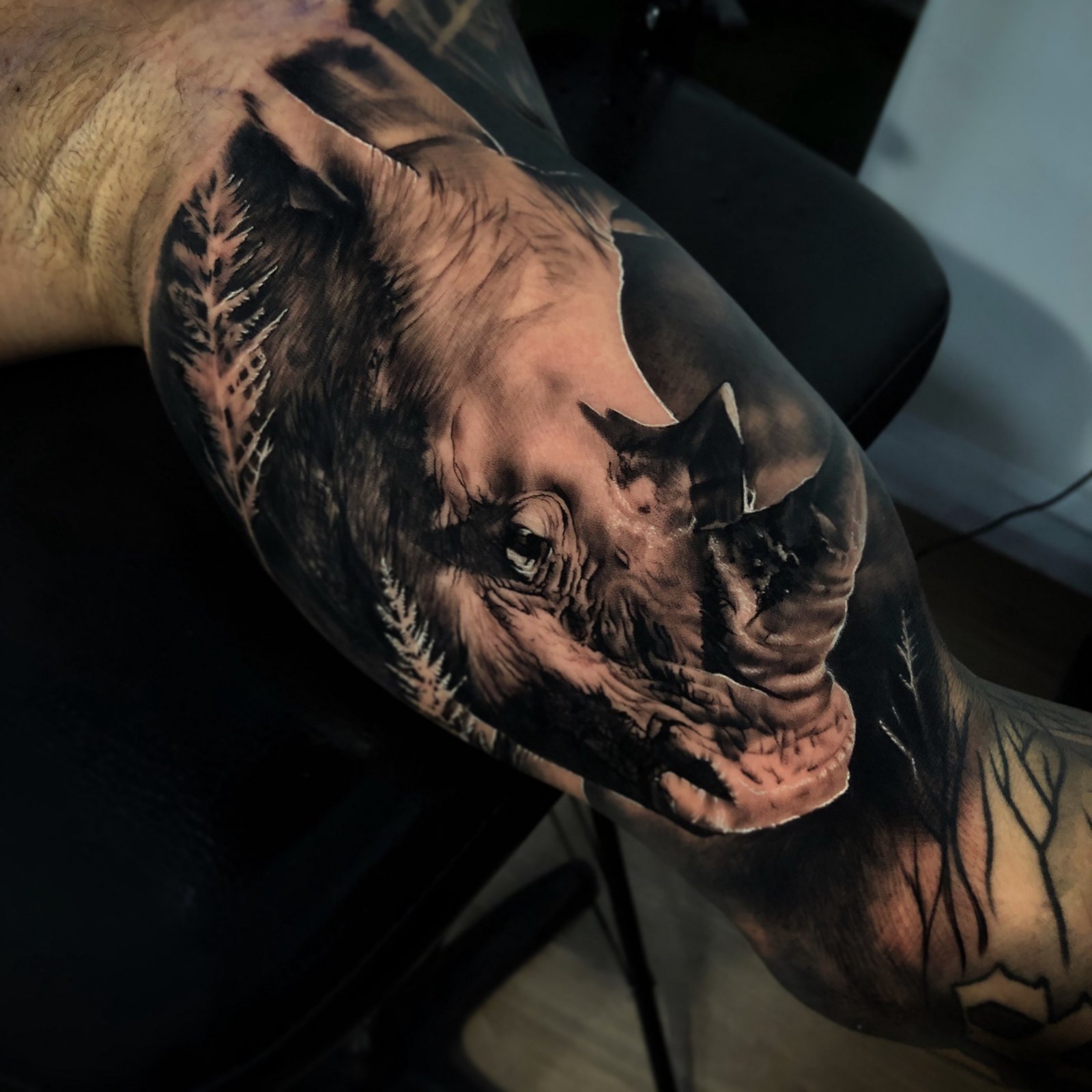 1bq2-igy_v7nykq86jotraq-1 Tatuagem realista de rinoceronte com detalhes em preto e cinza no braço de uma pessoa.