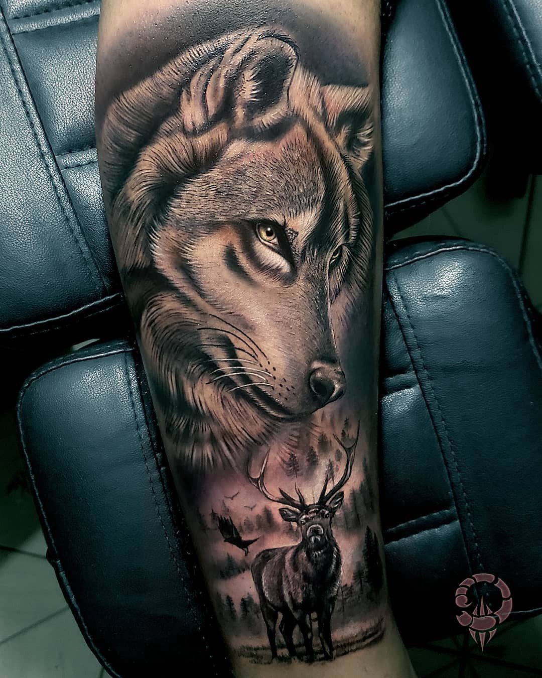 1fblzuw1ocpstcrititdi6w Tatuagem em braço com desenho de lobo e cervo em cenário de floresta sombria.