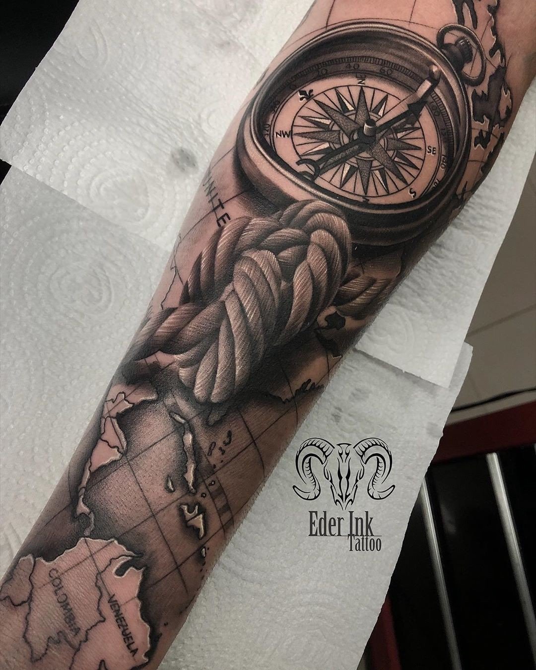 1hzlkxv2rgmlpp-pj7t_zea Uma tatuagem no braço com uma bússola, corda e mapa detalhado.