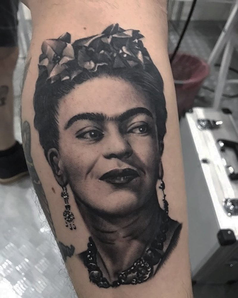 1kdh-n4xj8wpom6qpeek9ba-1 Uma tatuagem detalhada de um rosto feminino com adereços de cabelo, brincos e colar, feita no braço.