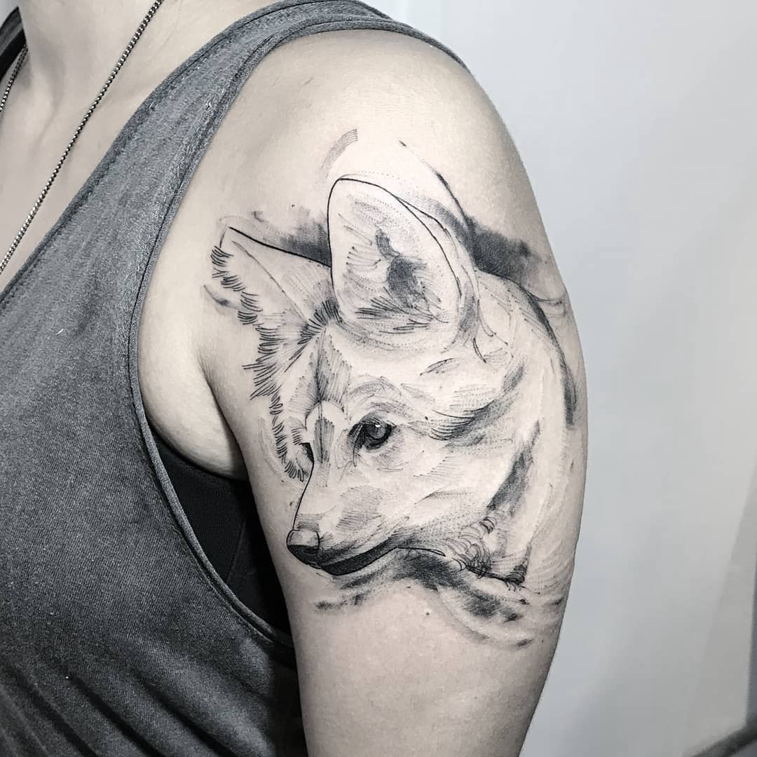 Pessoa com tatuagem de lobo estilizado no braço, usando camiseta sem mangas.
