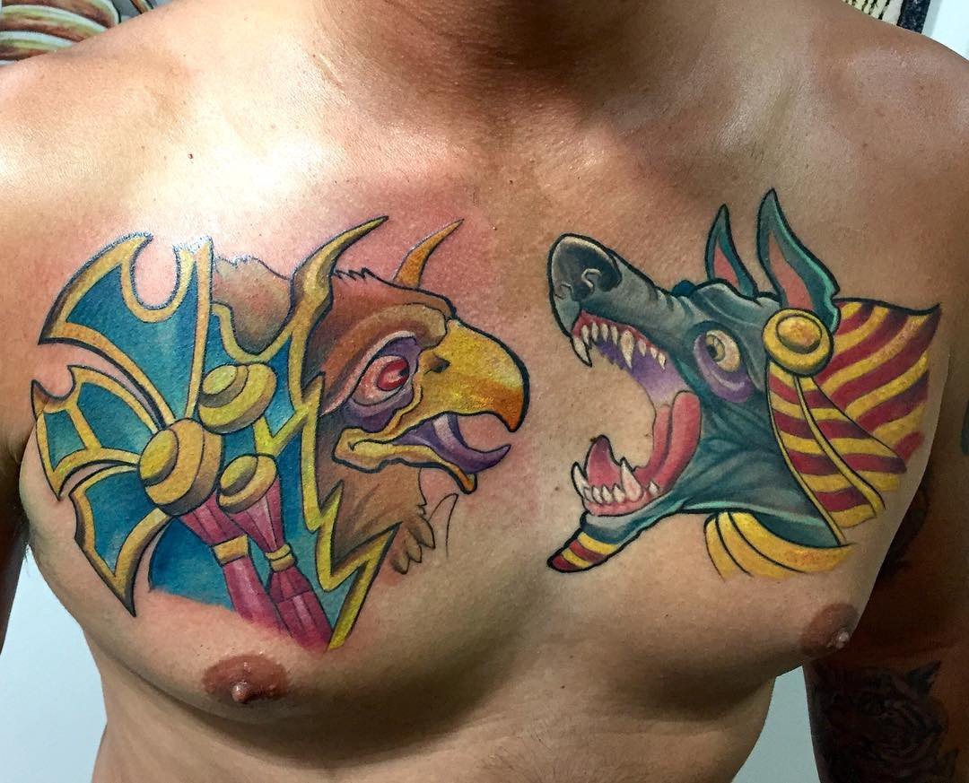 1kwwhirzpazzcb7t-_2-owq-1 Duas tatuagens coloridas no peito, uma de criatura com cabeça de ave e outra de criatura com cabeça de chacal.