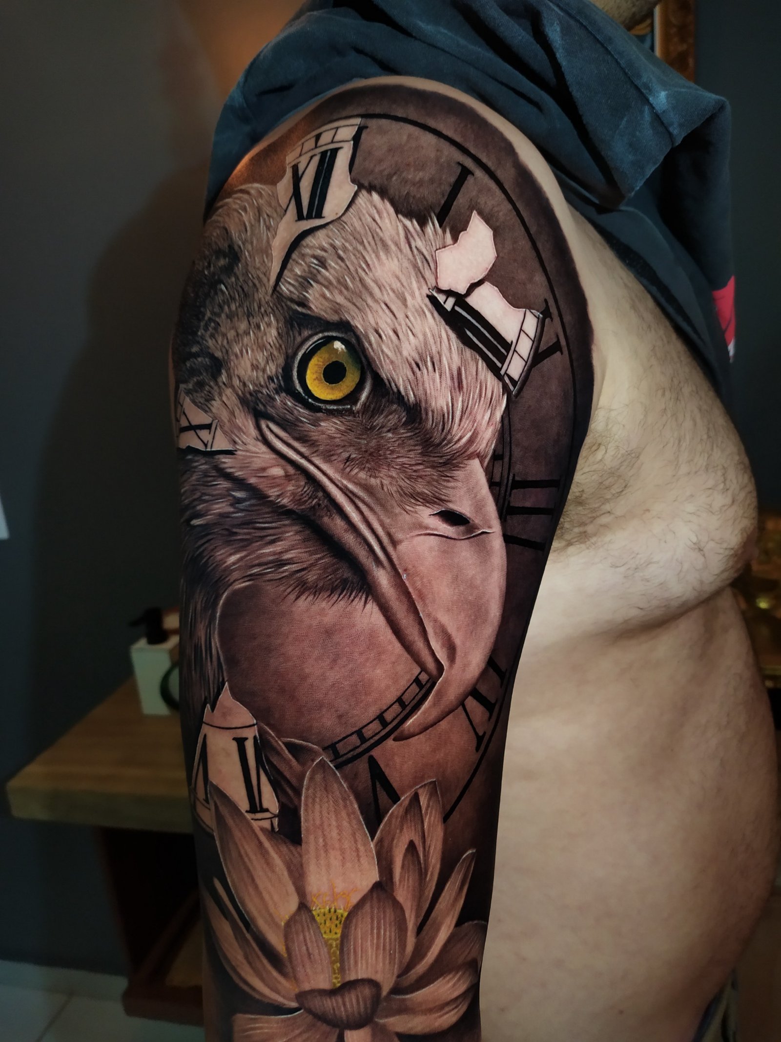 1ompdynjdjegumh6dex41tw-1 Tatuagem no braço com desenho de ave, relógio de números romanos e flor de lótus.