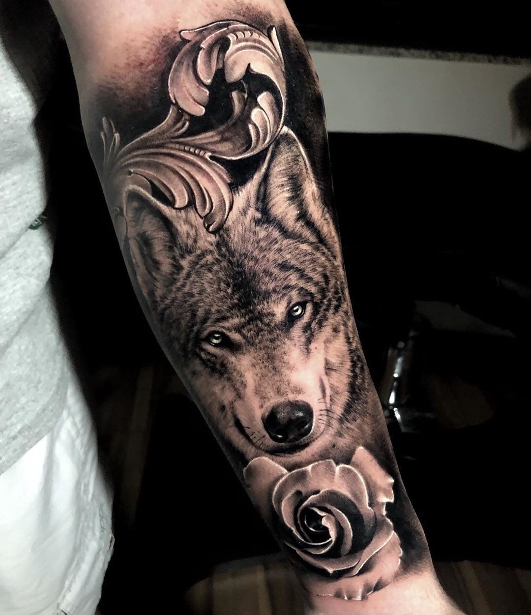 1ovm8foum8h67xckdw9tuhg Tatuagem detalhada de lobo com rosa e ornamentos no braço de uma pessoa.