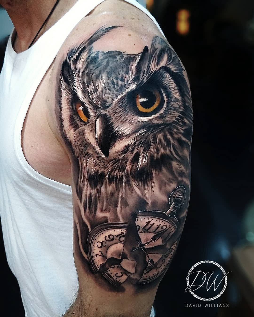 1r8m4bwn4mkvdectskmxb9g Tatuagem no braço de uma coruja realista sobre um relógio, em tons de cinza e detalhes em amarelo.