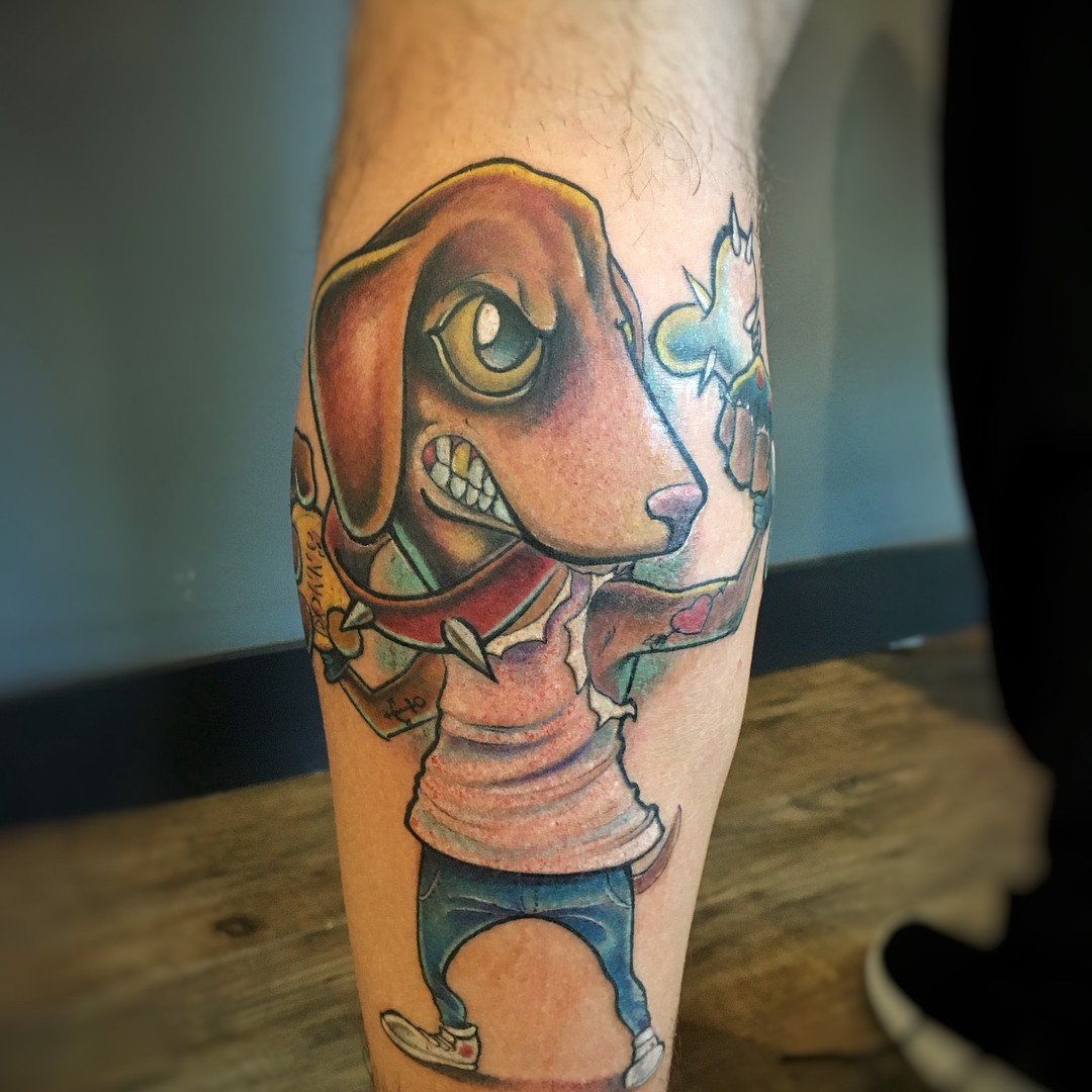 1x1yfl5fc7j4jnjax6q31sa-1 Tattoo de cachorro antropomorfizado segurando um sorvete, com expressão determinada, em uma perna.