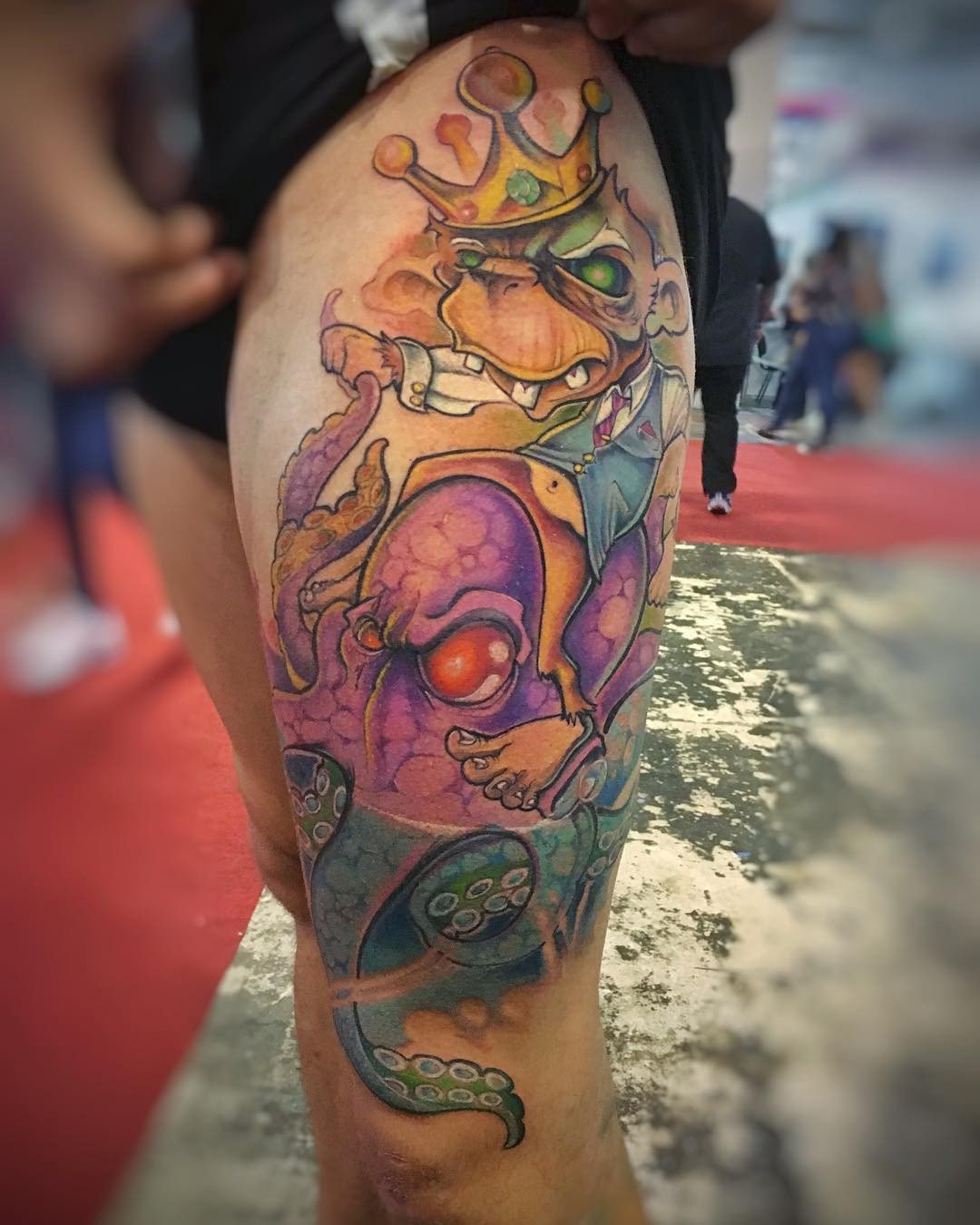 1x5daswbwtpgymruu9dqcuw-1 Tatuagem colorida em perna com desenho de personagem com coroa e tentáculos de polvo.