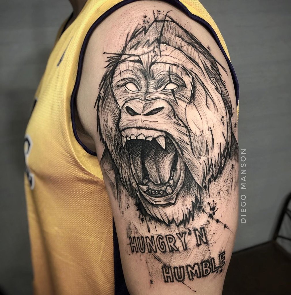 w1010 Desenho de gorila rugindo tatuado no braço, com as palavras "Hungry 'N Humble" abaixo.