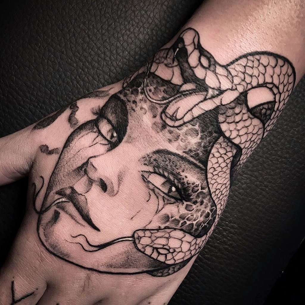 w1024-139 Uma tatuagem em uma mão, mostrando um rosto feminino com uma cobra ao redor.