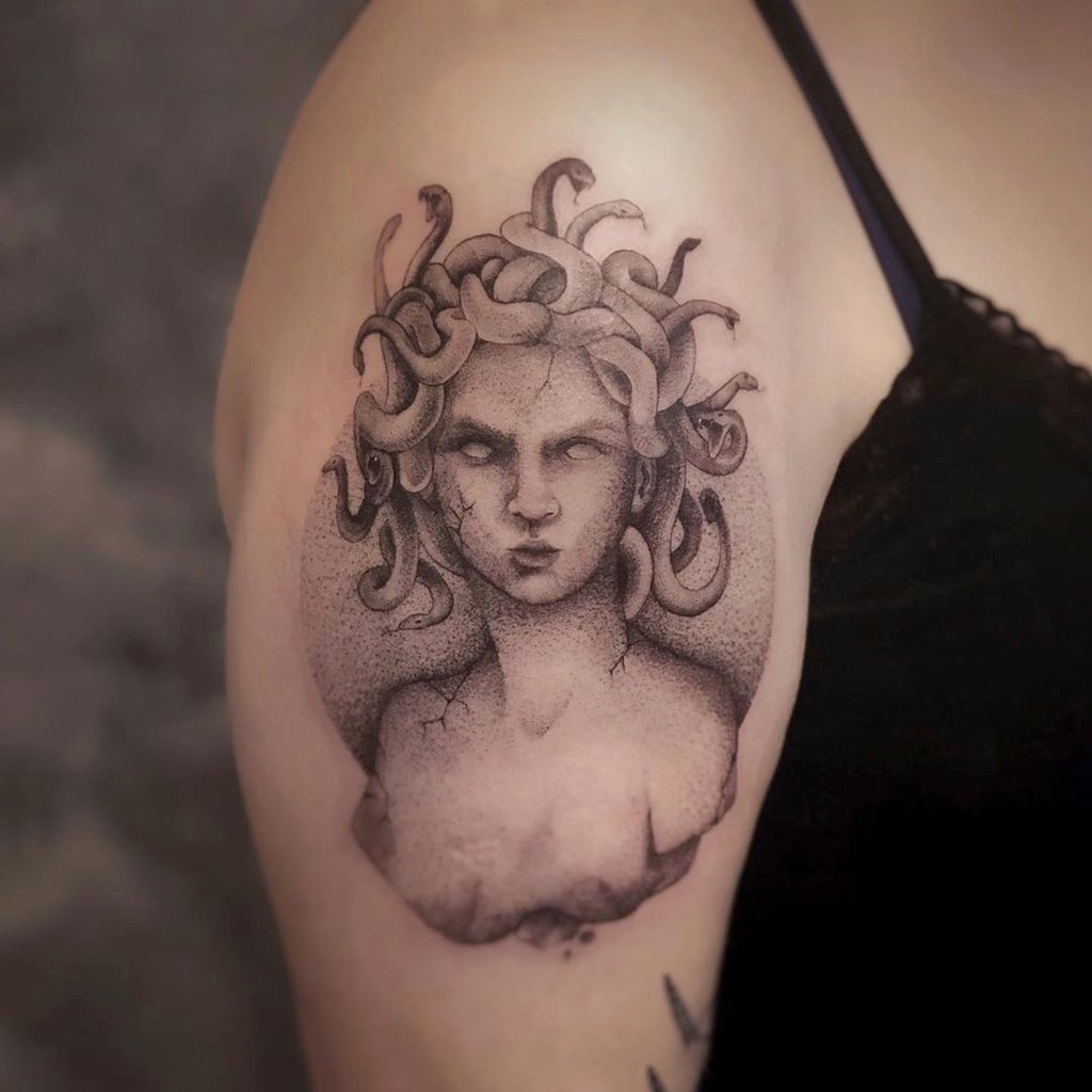 w1024-143 Tatuagem de uma figura mitológica com cabelos de serpentes no braço de uma pessoa.