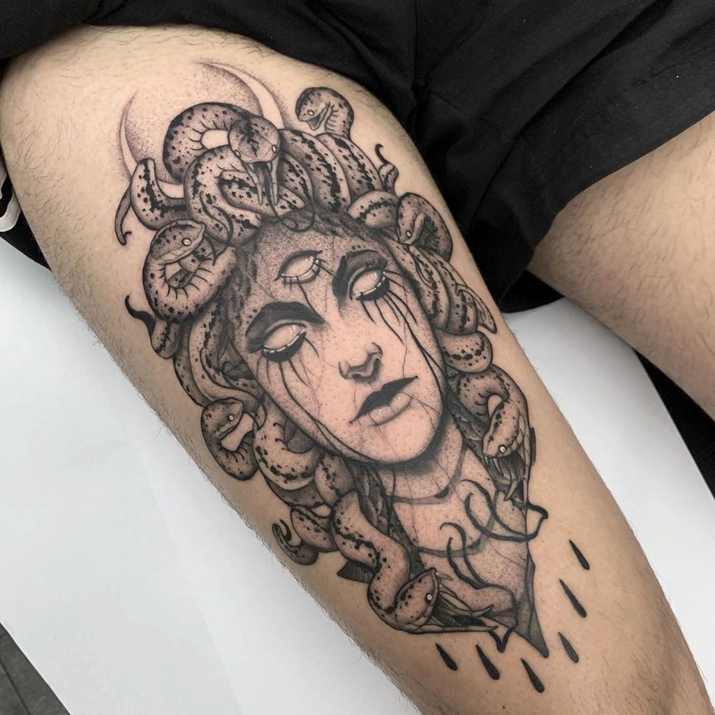 w1024-161 Uma tatuagem de rosto feminino com cobras na cabeça, olhos brancos e detalhes sombreados no braço de uma pessoa.