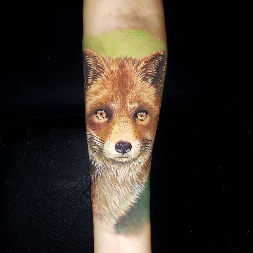w1024-56 Uma tatuagem realista de raposa no antebraço, com detalhes em marrom e fundo esverdeado.