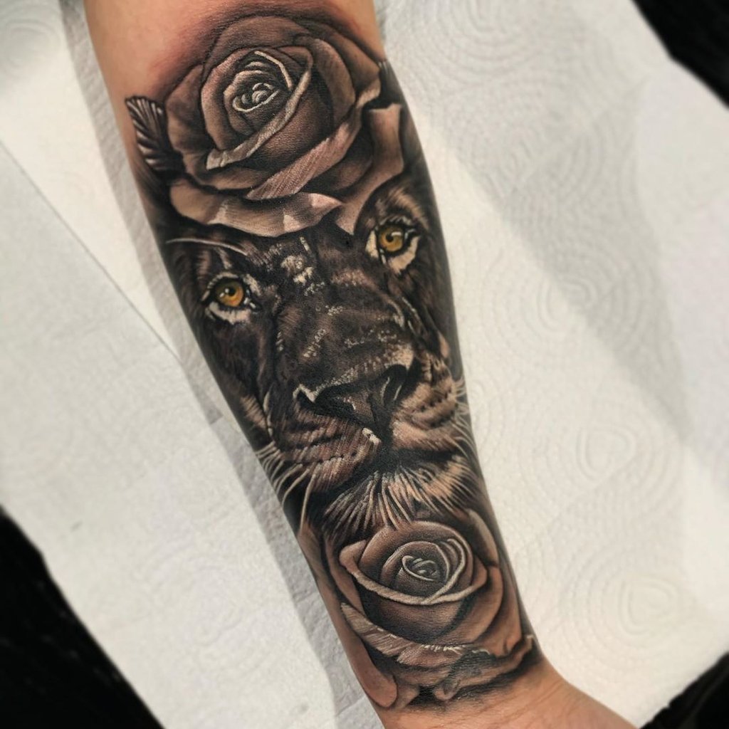 w1024-65 Uma tatuagem de leão com rosas em um braço humano, capturada em close.