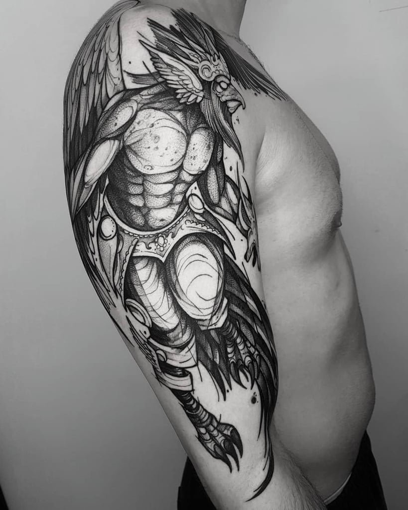 w819-13 Homem com tatuagem detalhada de figura mitológica com asas, cobrindo o braço e ombro, em estilo preto e cinza.