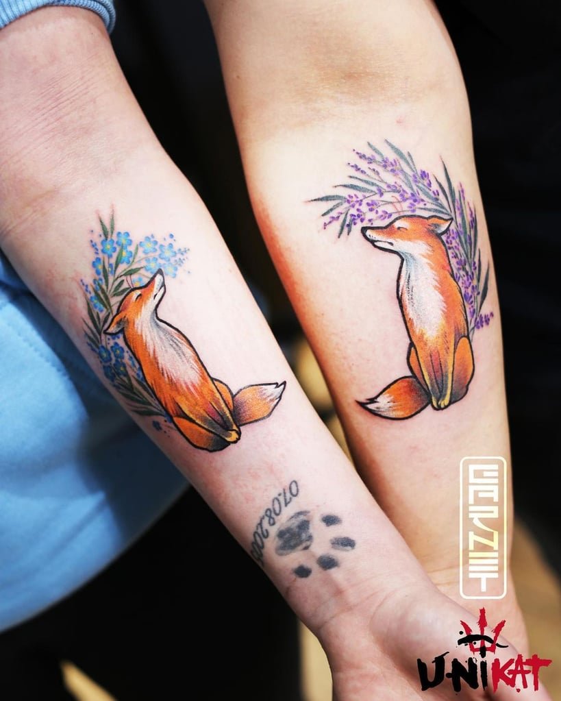 w819-229 Dois braços com tatuagens idênticas de raposa cercada por flores coloridas.