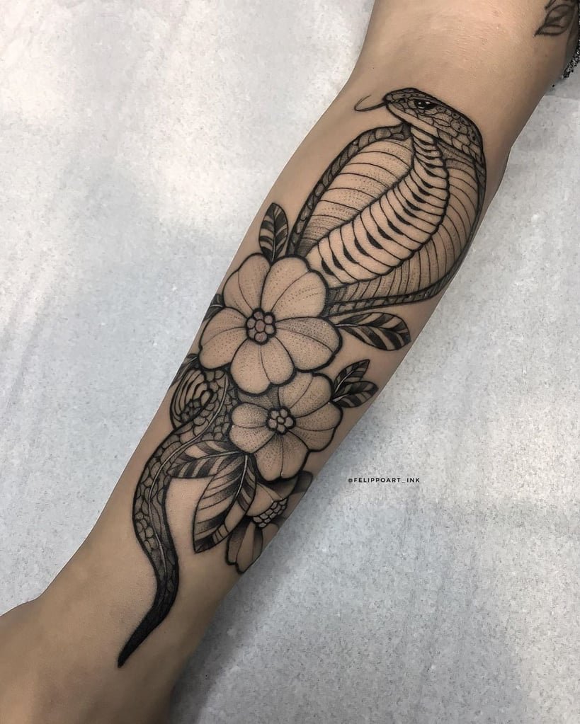 w819-23 Braço com tatuagem de cobra entre flores e folhas em estilo preto e cinza.