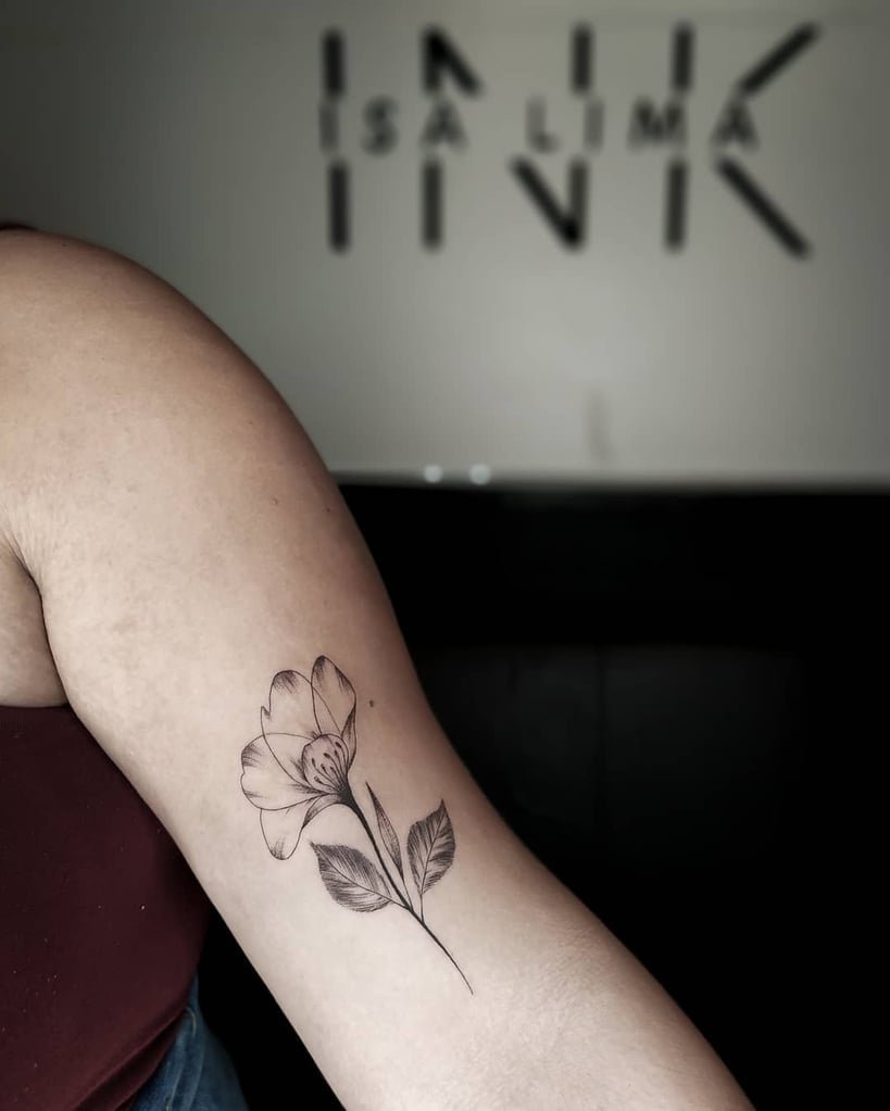 w819-32 Pessoa com tatuagem de flor delicada no braço, em ambiente de estúdio de tatuagem.