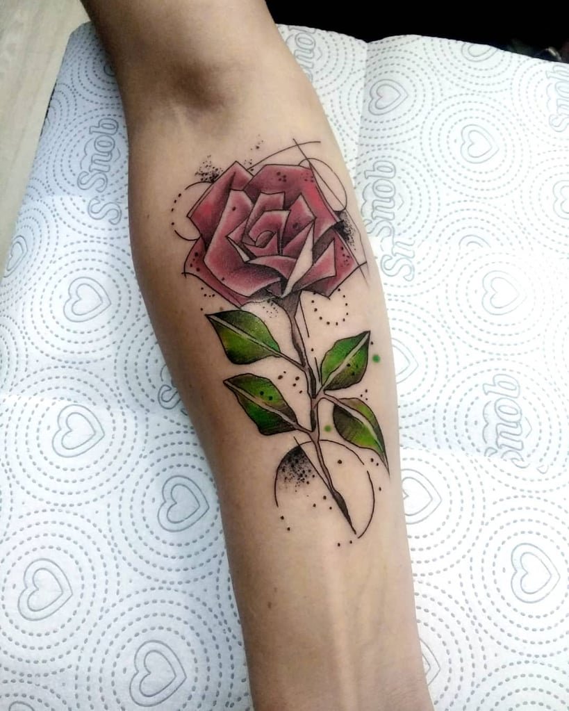 w819-42 Braço com tatuagem de rosa estilizada em tons de vermelho e verde, sobre papel com corações.