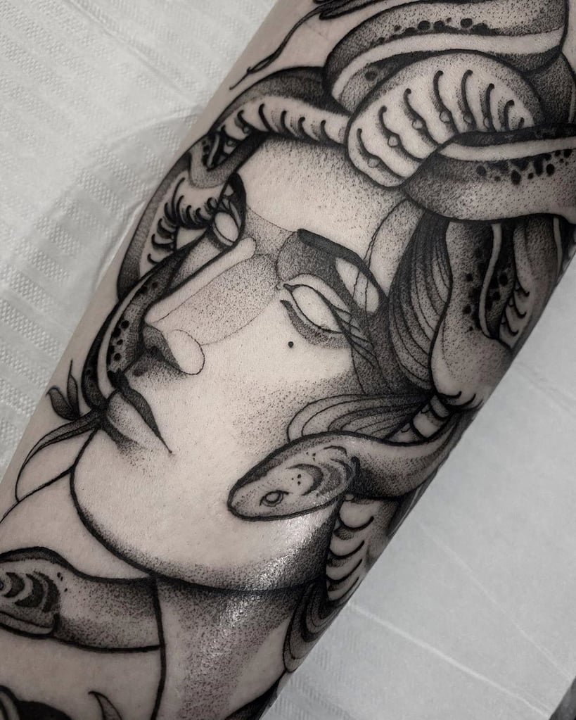 w819-89 Uma tatuagem em preto e cinza de um rosto com serpentes entrelaçadas.