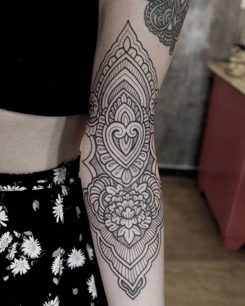 w820 Braço com tatuagem de mandala detalhada em preto, destacando padrões geométricos e florais.