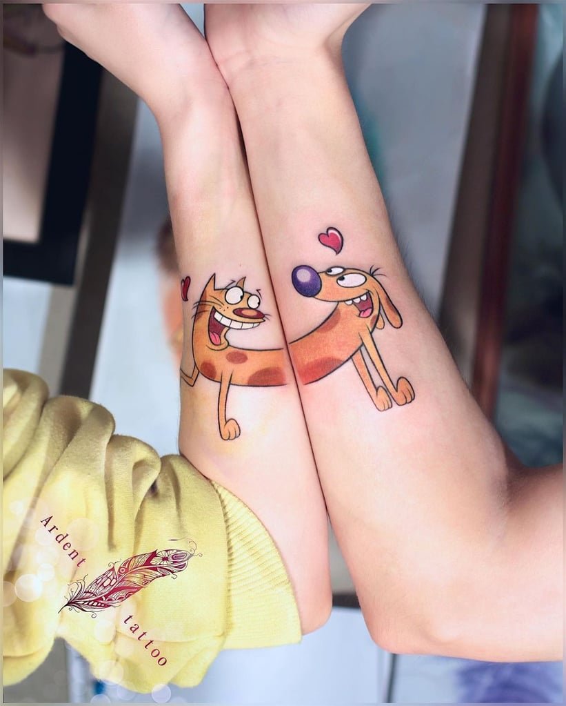 w821-7 Dois braços com tatuagens coloridas de personagens animados ligados, exibindo corações acima.
