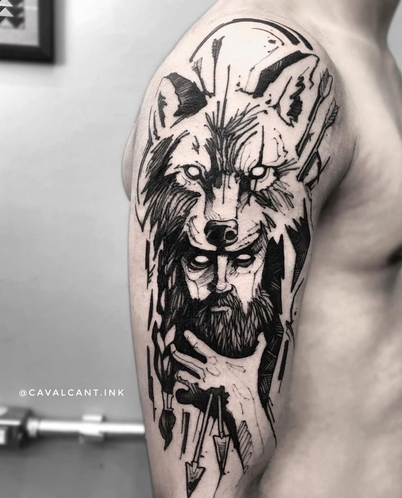 Tatuagem no braço com desenho de lobo e figura humana estilizada, traços em preto e cinza.