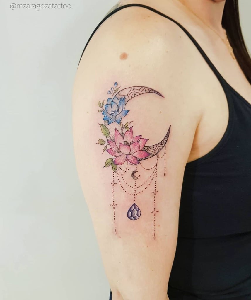 w857-2 Tatuagem no braço com flores coloridas e lua crescente decorada com correntes e um pingente.