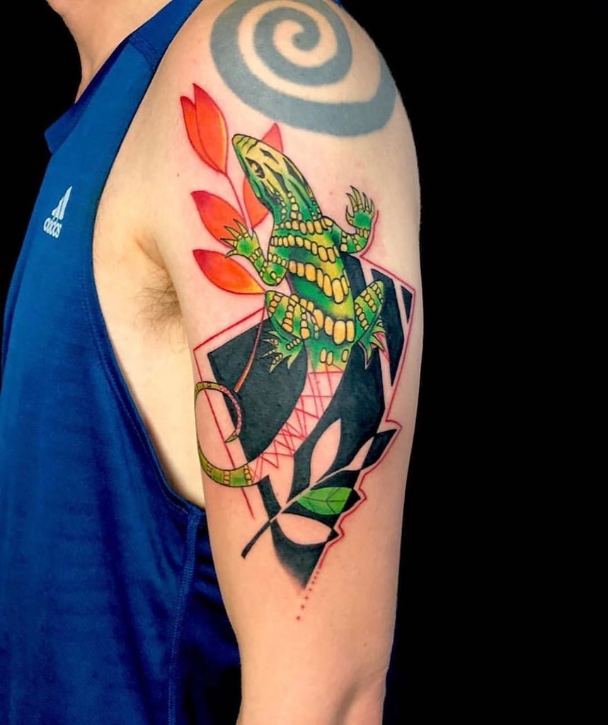 w859 Pessoa com tatuagem de lagarto colorido no braço, usando camiseta azul.