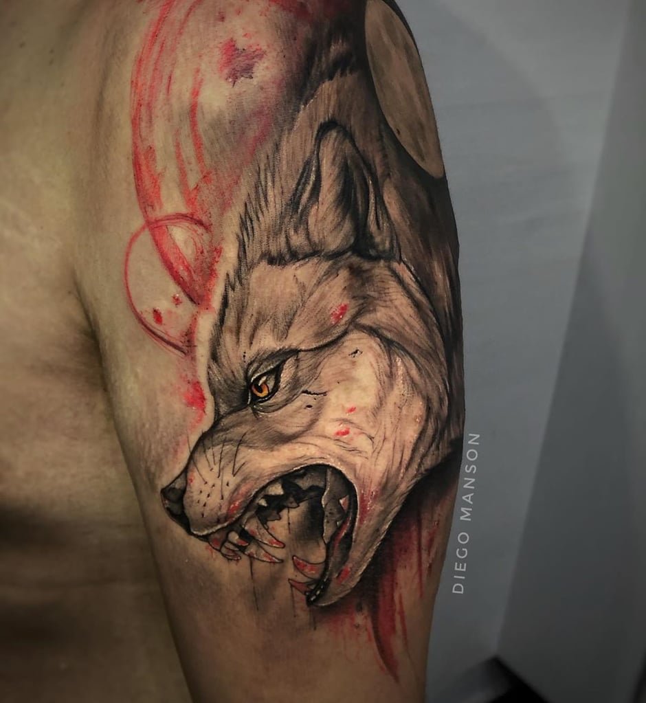 w940 Tatuagem de lobo com expressão feroz e detalhes em vermelho no braço de uma pessoa.