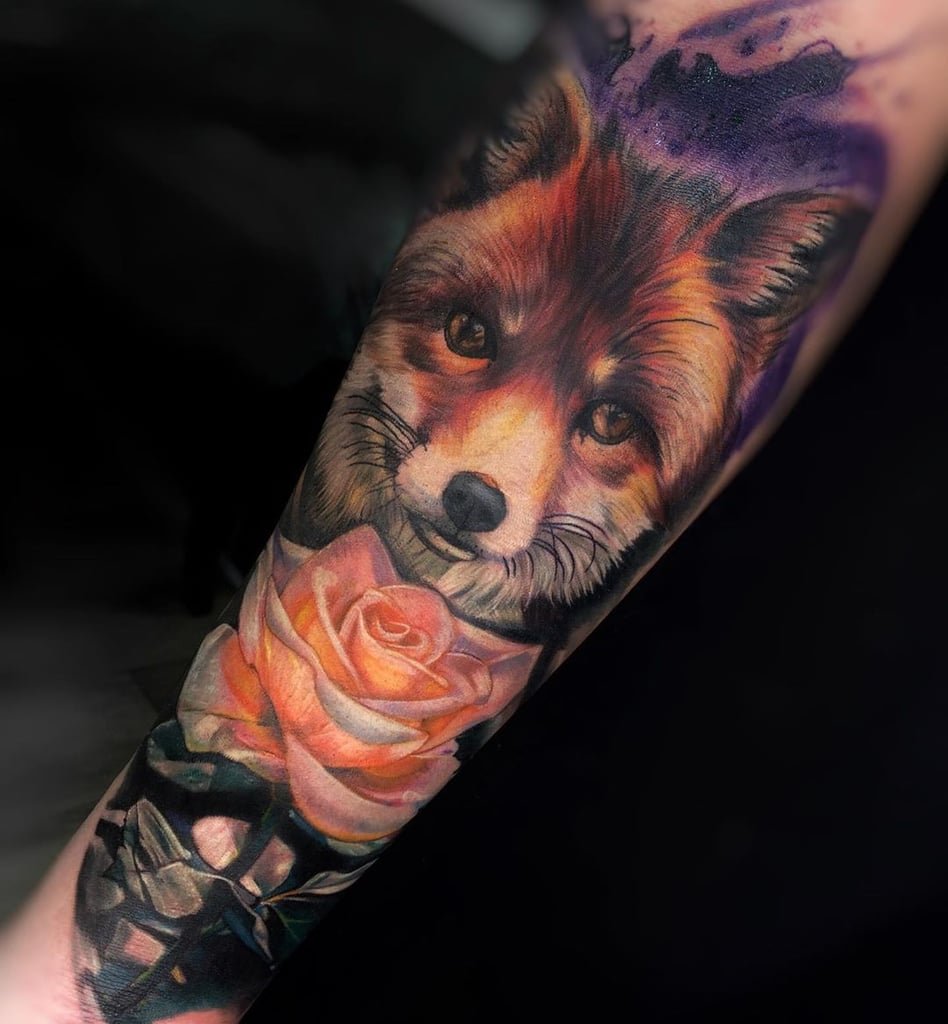 w948 Tatuagem de raposa realista com flor rosa no braço, destacando tons vibrantes e detalhes sutis.