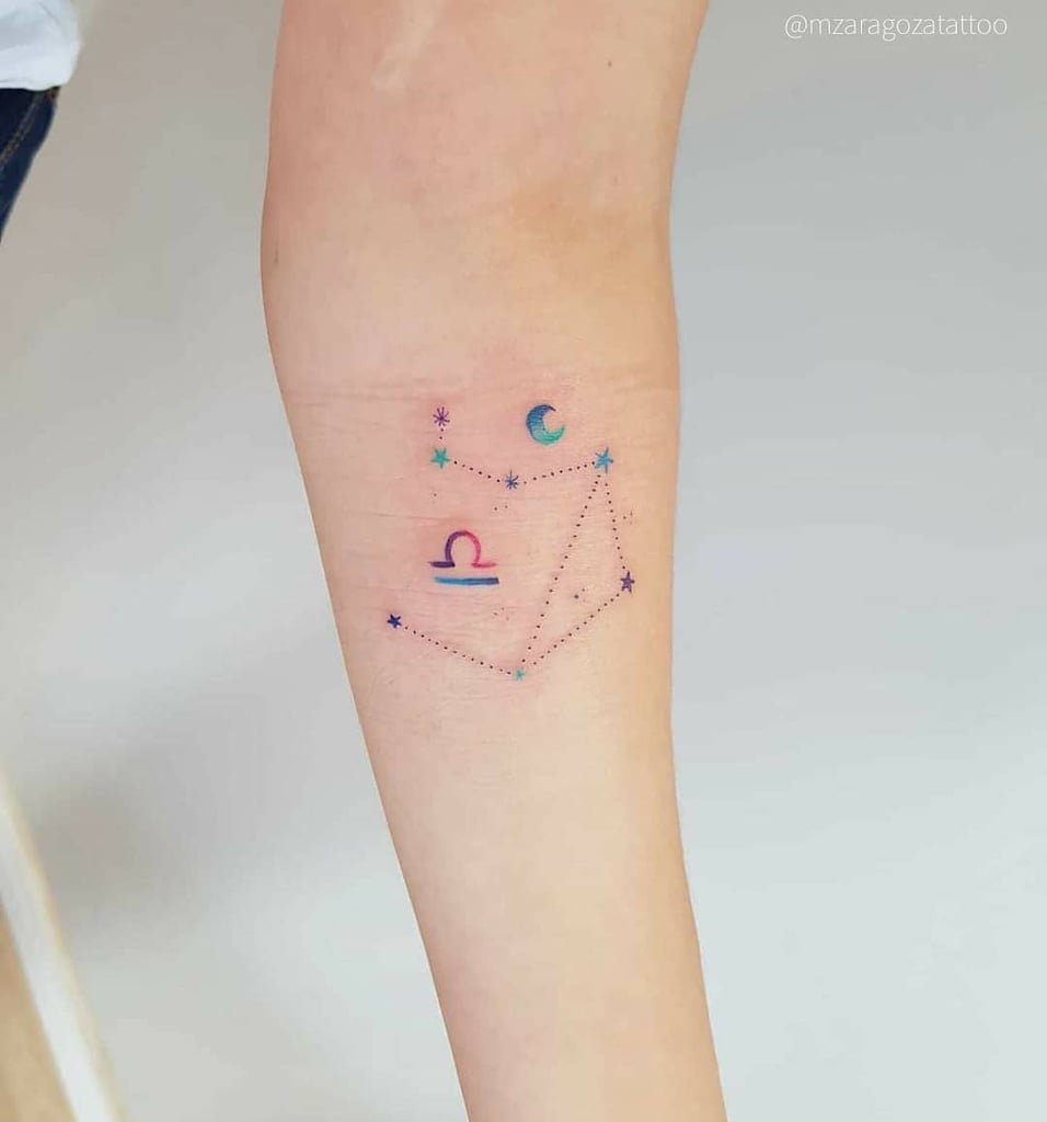 w956-1 Uma tatuagem colorida no braço com símbolo astrológico, estrelas e uma lua.