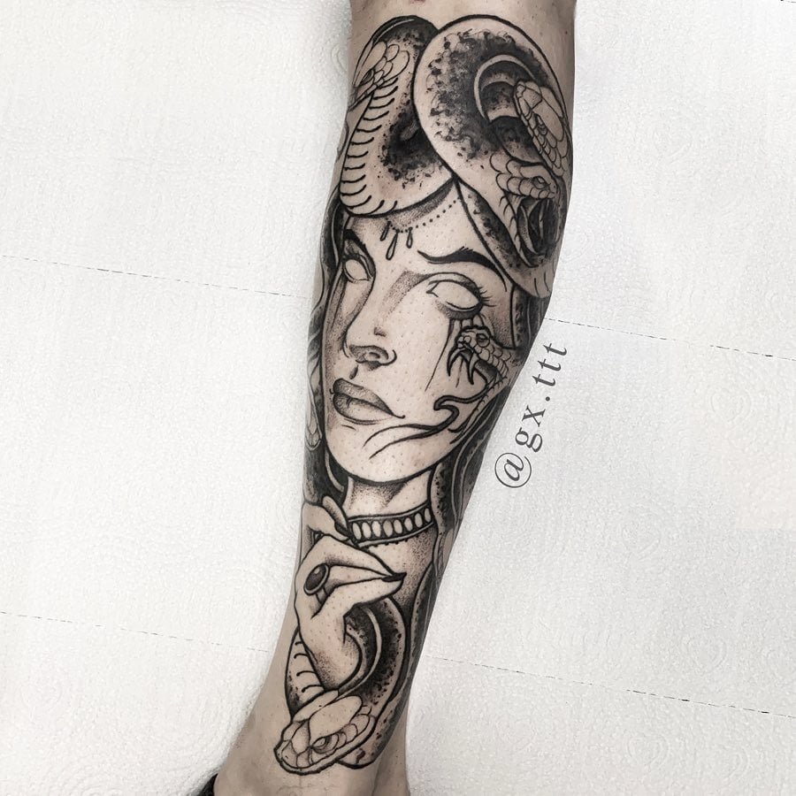 w9999-30 Tatuagem em uma perna representando uma figura feminina com cobras ao redor da cabeça.