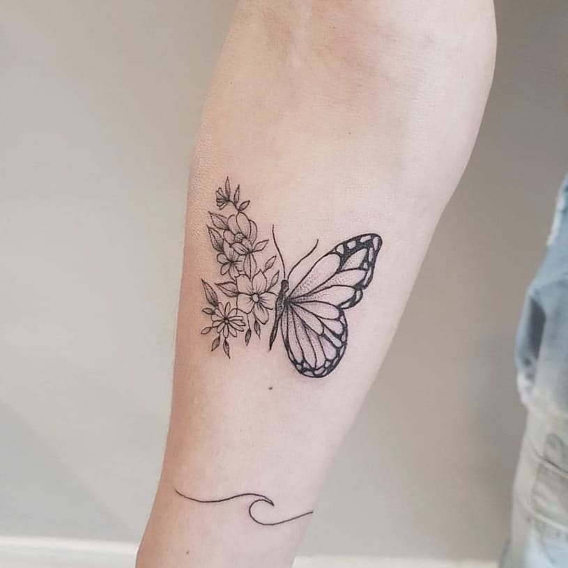 w9999-85 Tatuagem de borboleta e flores pretas em um braço, com um traço curvo logo abaixo.