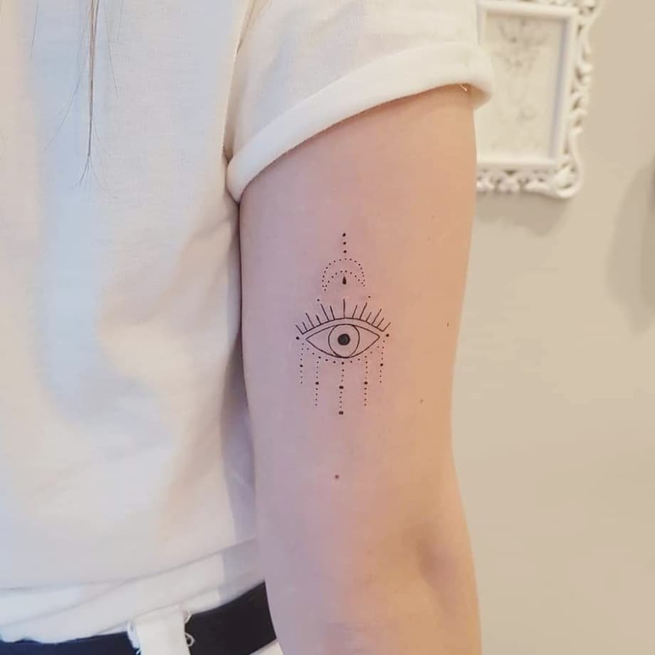 w9999-87 Pessoa com tatuagem minimalista de olho no braço, usando camiseta branca.