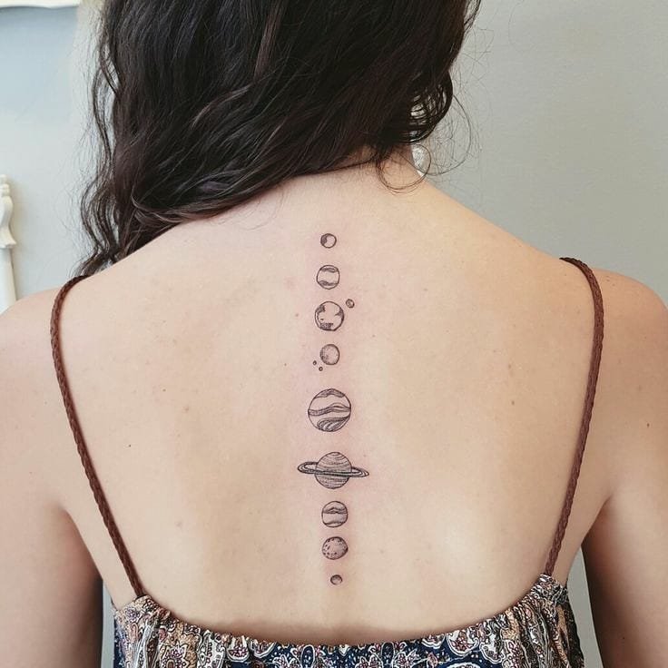 w9999-88 Pessoa com tatuagem de sistema solar alinhada verticalmente nas costas, usando blusa com alças finas.