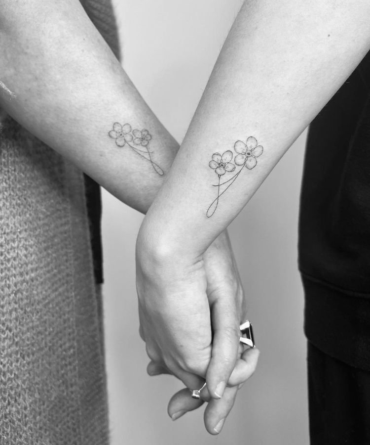 1-tatuagem-mae-filha-flor-1 mãe e filha de mãos dadas com tatuagem de flores na lateral do braço