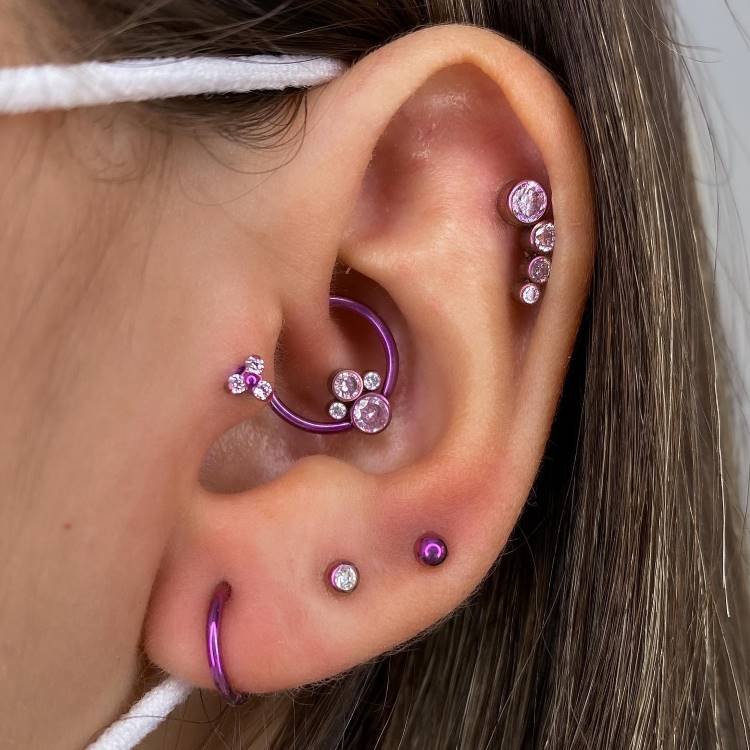 Projeto auricular anodizado em fúcsia, com piercing na hélix, tragus, daith e lóbulo.