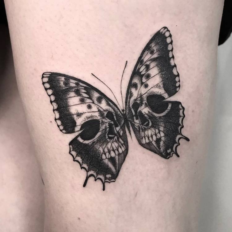 caveira-borboleta-braco Tatuagem de borboleta com sombreamento e estampa de caveira, feita no braço de um homem de pele clara.