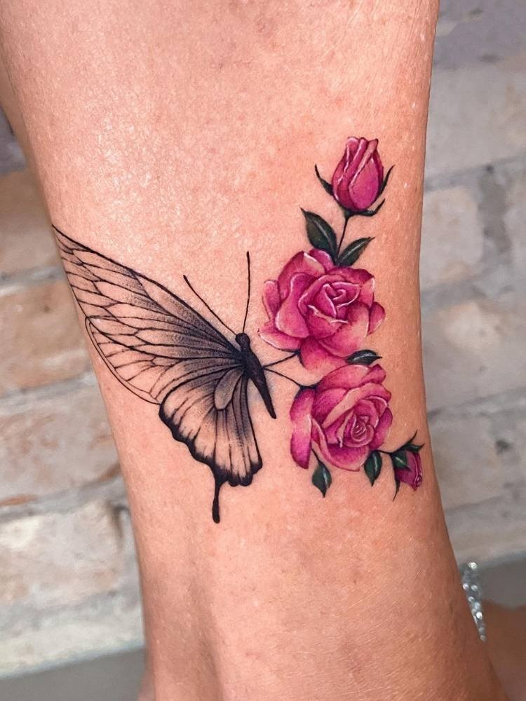 flores-colorida-tattoo-borboleta Tatuagem de borboleta com asa metade em traços finos pretos com sombreado e a outra metade com flores rosas. Feita no braço de uma mulher de pele clara.
