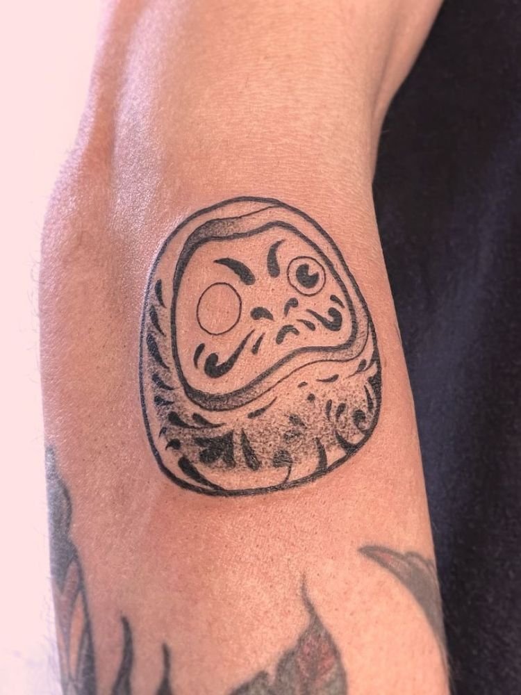 imagem-33 tatuagem de daruma feita próximo ao cotovelo.