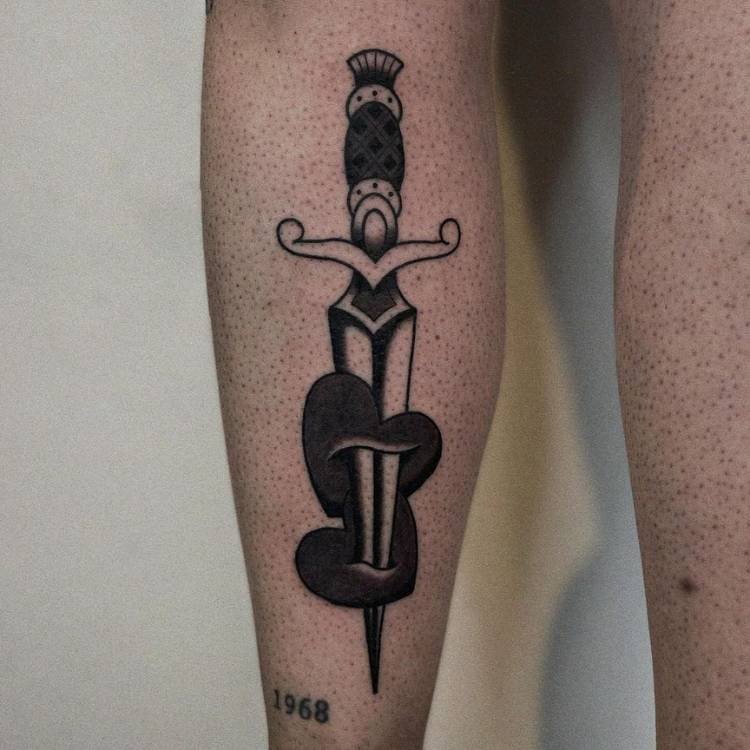 Adaga old school em preto enfiada em dois corações também em preto, tatuada em uma pessoa de pele clara