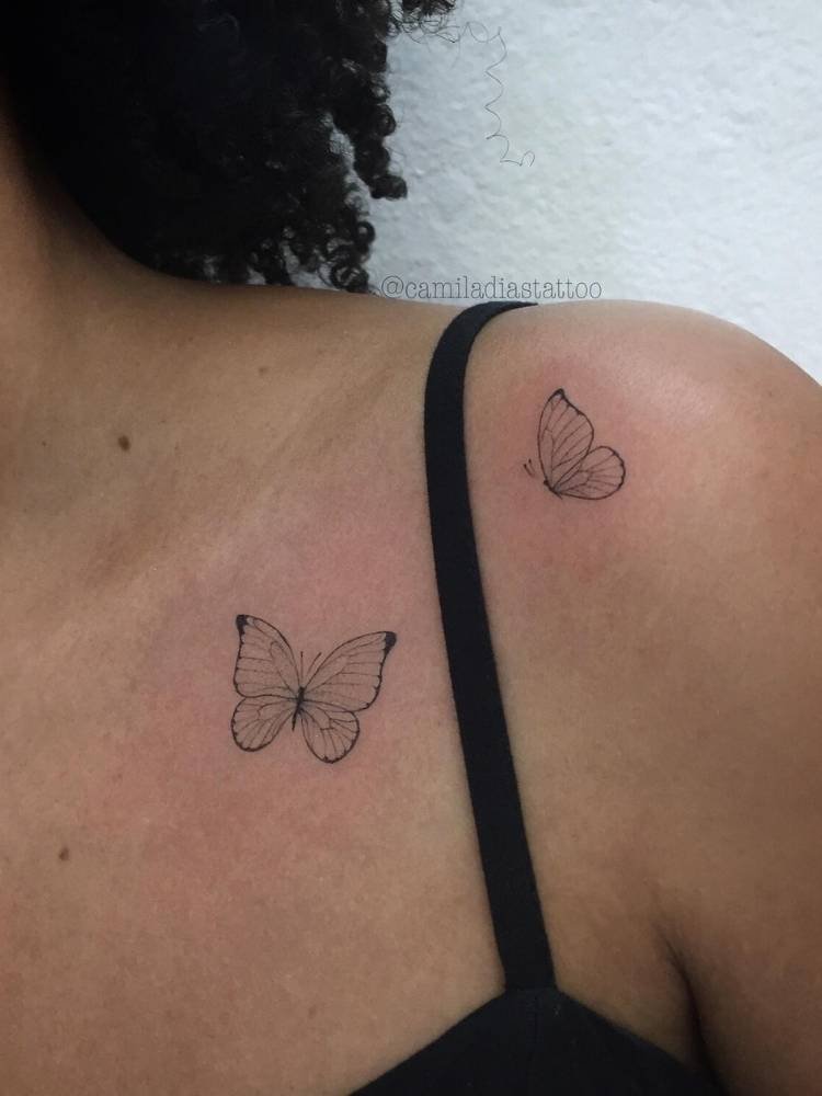 ombro-tatuagem-borboelta-delicada-traco-fino Duas pequenas borboletas em traço fino no ombro de uma mulher de pele morena.