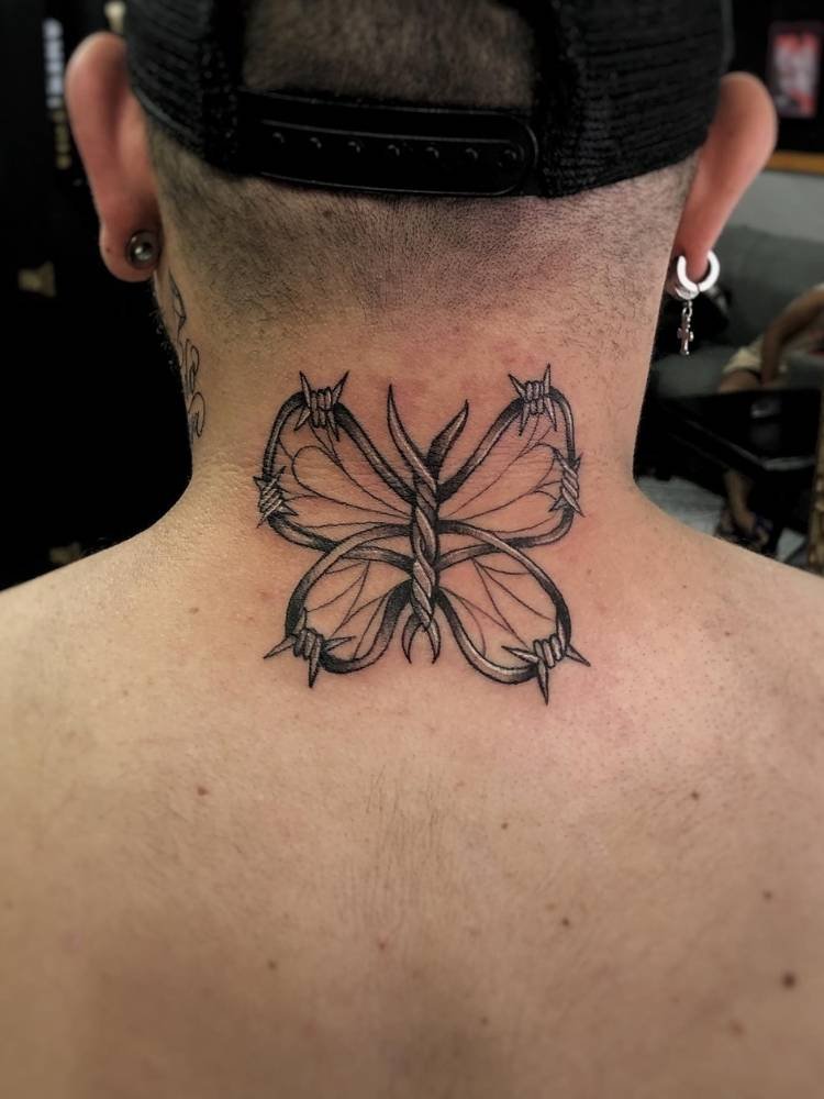 pescocco-borboleta-espinhas Tatuagem de borboleta com traços grossos e espinhos nas asas. Feita na nuca/costas de um homem de pele clara.