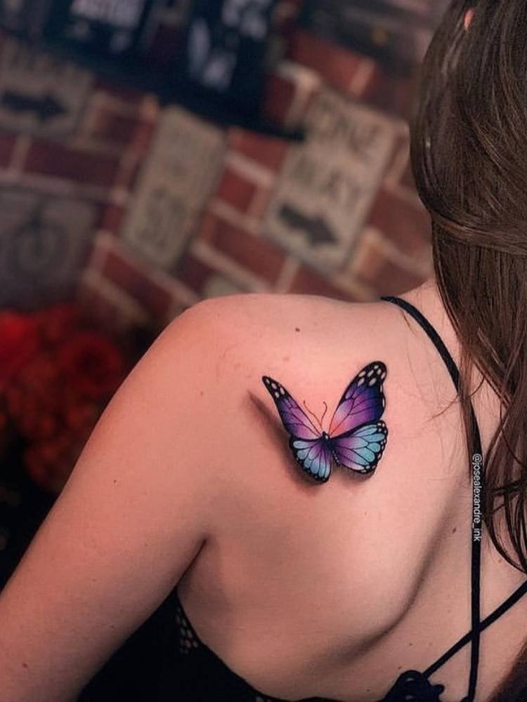 sombreamento-borboleta-roxa-e-azul Tatuagem de borboleta roxa e azul com sombreamento na parte de trás do ombro de uma mulher de pele clara.