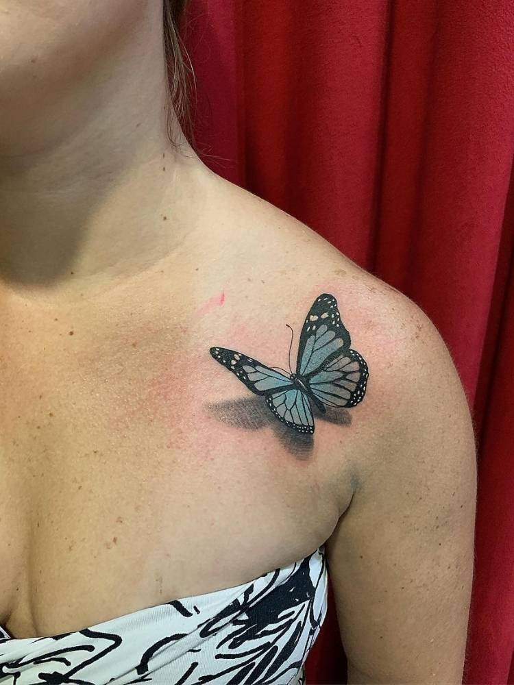 sombreamento-ombro-borboleta Tattoo de borboleta-azul com sombreamento efeito 3D no ombro de uma mulher de pele clara.