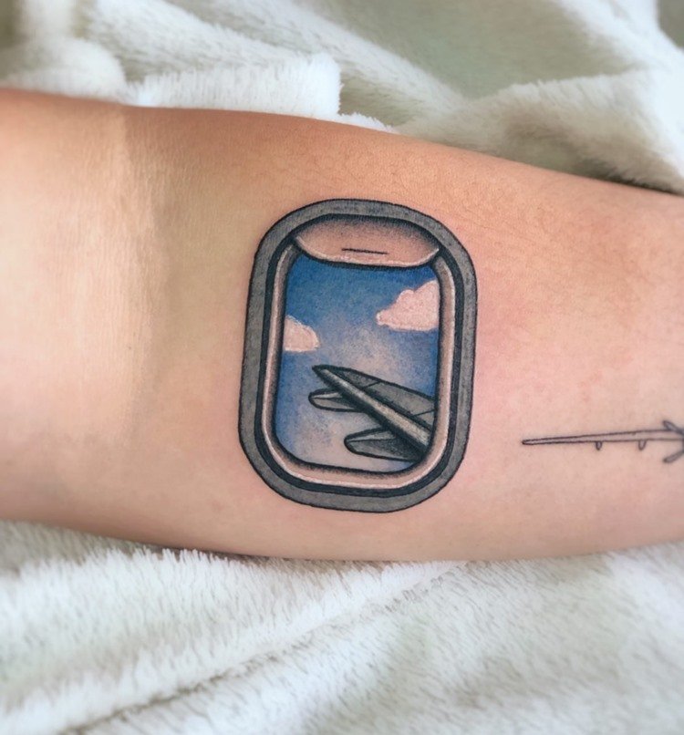 Tatuagem colorida de janela de avião com visão de asa e nuvens em um abraço