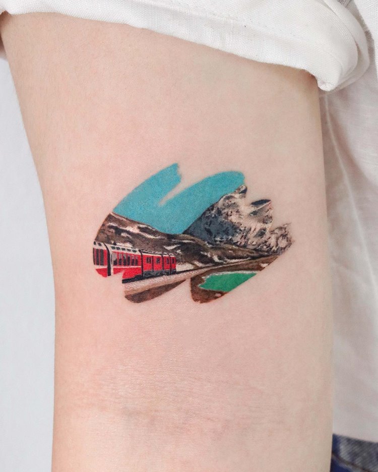 Tatuagem de tinta com trem andando em meio aos alpes